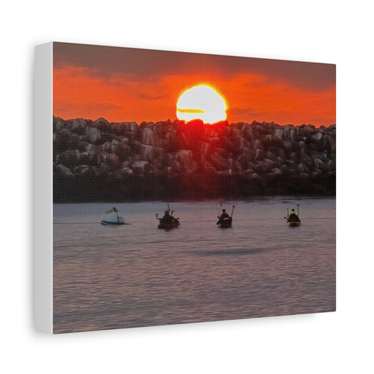 Kayakers glide peacefully through a harbor as the sun dips behind the rock break wall